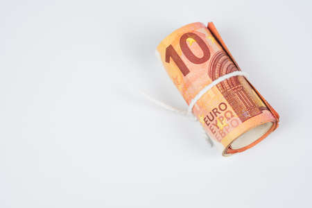 Roll of ten euro banknotes with white robe isolated on white background.