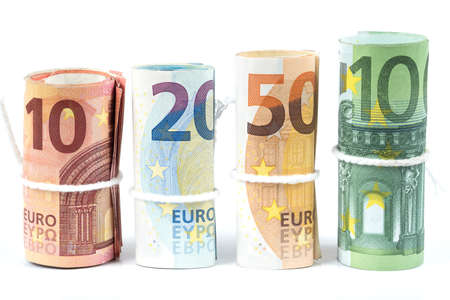 Several rolls of euro banknotes stacked by value from ten, twenty, fifty and one hundred euros with white rope band isolated on white background. Money bills rolled each other in different positions.の写真素材