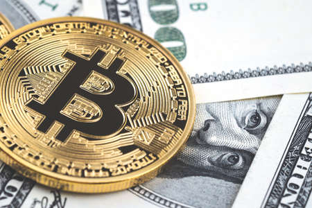 Close up gold bitcoin coins on one hundred US dollar bills background. Cryptocurrency, New digital...