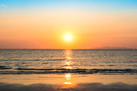 Beautiful sunset over sea and tropical beach in summer time. Natural background of sunset dawn and sunrise with bright dramatic scenic sky. Sun over skyline, Blazing sun and golden light in evening.の写真素材
