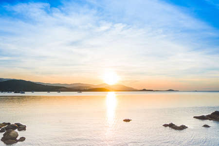 Beautiful sunset over sea and tropical beach in summer time. Natural background of sunset dawn and sunrise with bright dramatic scenic sky. Sun over skyline, Blazing sun and golden light in evening.の写真素材