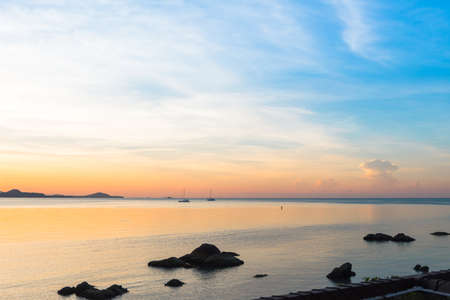 Beautiful sunrise and sunset with blue clouds over horizon clam blue sea and mountain background in morning and evening. Scenic seascape with golden light in summer.の写真素材