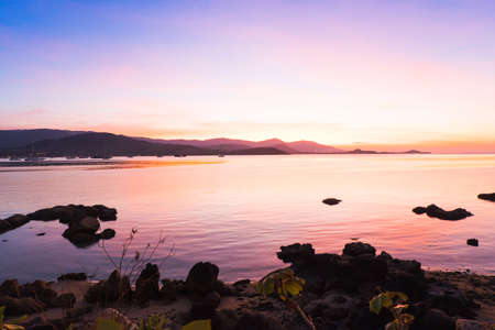 Colorful of dramatic sunset and sunrise with twilight orange sun blazing and blue sky with mountain and calm tropical sea. Summer beach background.の写真素材