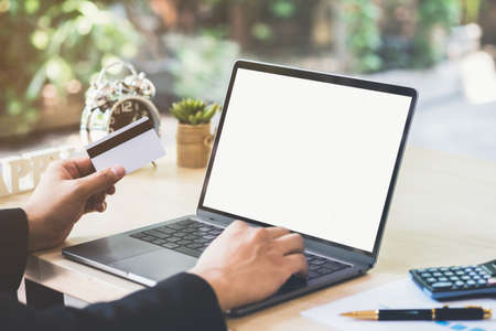 Businessman hand holding credit card and using laptop on desk with document and calculator. Man hand...