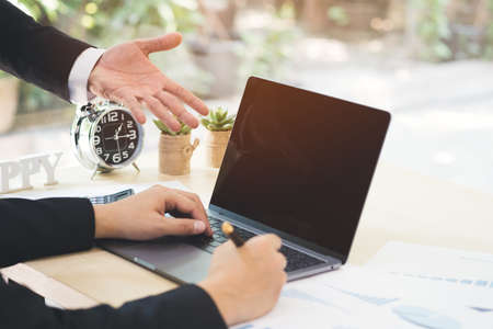 Businessman hand pointing on black blank screen laptop to explanation and takes note on business document in office while meeting. Business partner dissatisfied and complaint in bad work result.の写真素材