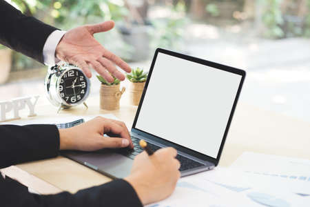 Businessman hand pointing on white blank screen laptop to explanation and takes note on business document in office while meeting. Business partner dissatisfied and complaint in bad work result.の写真素材