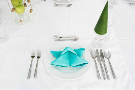 Table setting with beautiful flowers and color napkin placed on white plate for dining, festive event or wedding.の写真素材