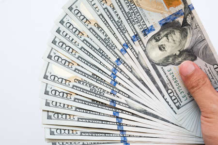 Close up hand holding money of one hundred dollar bills isolated on white background. Hand giving...