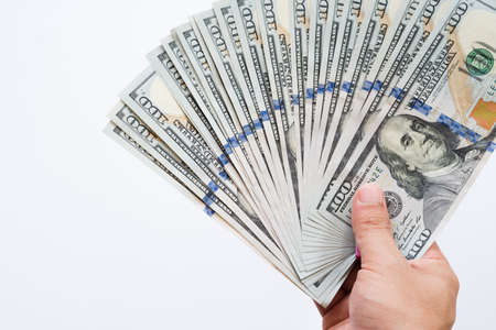 Close up hand holding money of one hundred dollar bills isolated on white background. Hand giving...