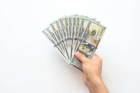 Human hand holding money of one hundred dollar bills isolated on white background. Hand giving one hundred dollar banknotes in financial, money exchange and donation concepts.の写真素材
