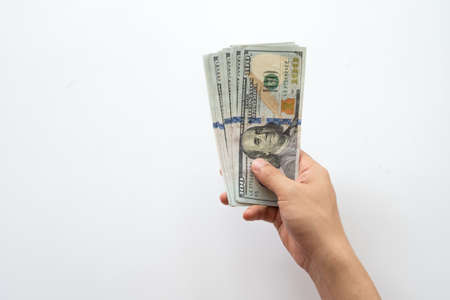 Human hand holding money of one hundred dollar bills isolated on white background. Hand giving one hundred dollar banknotes in financial, money exchange and donation concepts.の写真素材