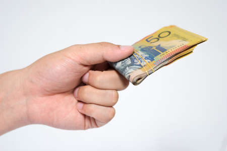 Close up  fifty Australia Dollar money bills in hand isolated on white background. Hand holding or giving money in financial and economy concepts.の写真素材