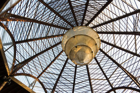Translucent roof or ceiling dome reflecting with morning sunlight golden steel and spiral lamp in modern and contemporary architecture as abstract architectural and industrial background or pattern.の写真素材