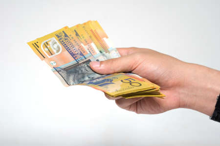 Close up  fifty Australia Dollar money bills in hand isolated on white background. Hand holding or giving money in financial and economy concepts.の写真素材