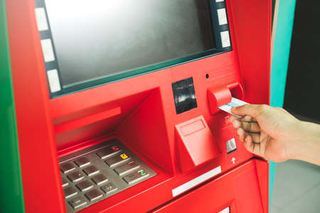 Man hand inserting debit or credit card to withdraw money with blank screen ATM machine. Selective focus on hand with credit card using Automatic Teller Machine. Banking and financial concept.の写真素材