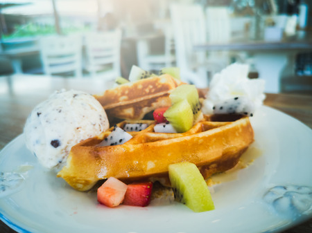 Waffles, ice cream, and fruit in a white plate.の写真素材