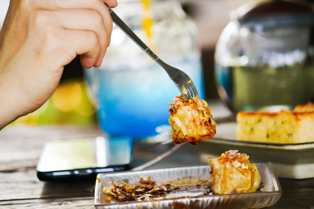 Hands holding a dipping fork Dumpling on the table.