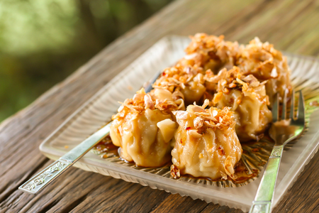 Shumai in a glass plate on a wooden table in the shop, looks delicious. Blurred backgroundの写真素材