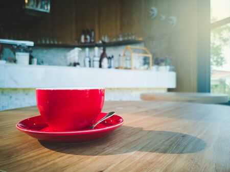 A red coffee mug placed on a wooden table in a coffee shop, has space for placing messages.の写真素材
