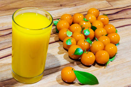 orange juice and deletable imitation fruits on table wooden. look chup thailand. little orange.