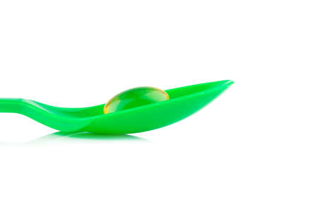 green plastic spoon.Capsules fish oil isolate on white background.の写真素材