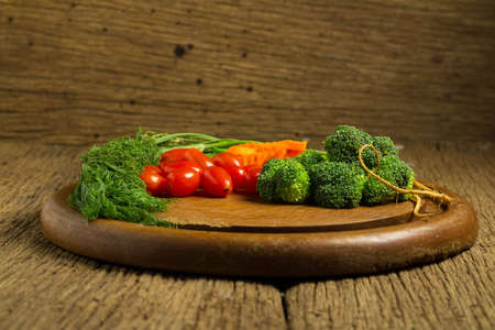 dill. baby tomatoes. carrot. broccoli. on old chopping borad wooden. on old wooden kitchen.の写真素材