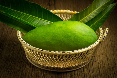 mango green in basket on wood. asian. morning.の写真素材