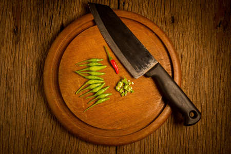 Round wood Chopping cutting board. chili peppers green and red. knife.