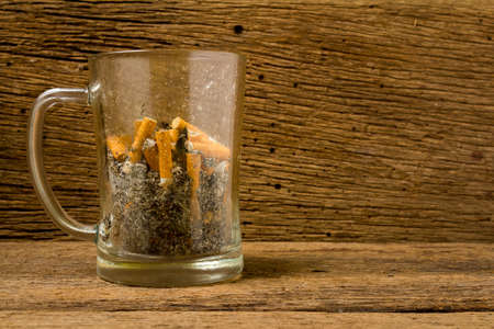 glass beer ashtray cigarette on old wood .の写真素材