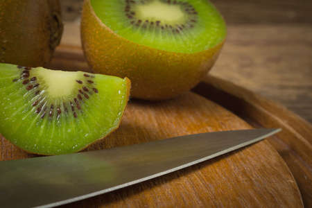 kiwi. sliced. half. fresh. cutting board with knife on old wood. closeup.の写真素材
