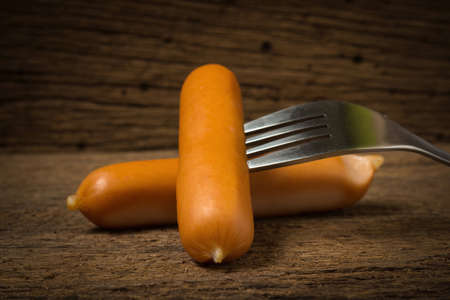 sausage on fork on old wood.