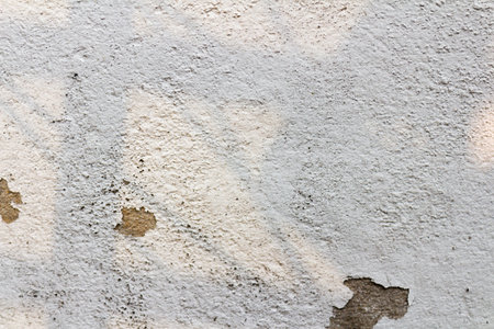 The white cement wall surface is peeling, dirty, old.の写真素材