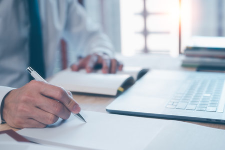 Businessman writing on notebook in office with computer laptop on table. Concept of finance planing and analyzes business and growth. working from home concept.の写真素材