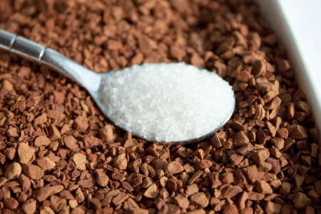 Spoon with sugar  against coffeeの写真素材