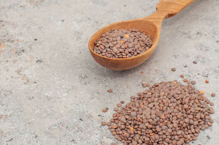 lentils in a wooden spoon, close-up on a gray background. horizontal orientation. Copy spaceの写真素材