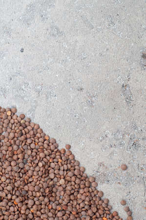 lentils in a wooden spoon, close-up on a gray background. vertical orientationの写真素材