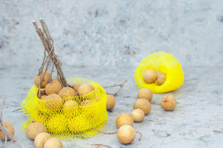 Exotic longan fruit in a string bag on a gray background. Place for text. Close-up. Copy space. Top view.の写真素材