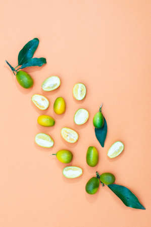 Fruit kumquat cut in half, on yellow background, vertical orientation. copy spaceの写真素材