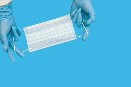 Protective medical white face mask on a blue background. View from above. Space for text. Close up, vertical orientation.の写真素材