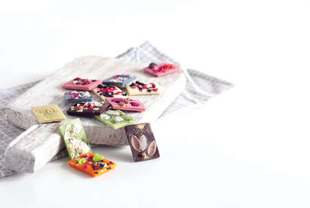 Natural Belgian chocolate of different flavors, made from organic products, matcha tea, green, blue, coconut, sprinkled with fruit chips, nuts, seeds.の写真素材