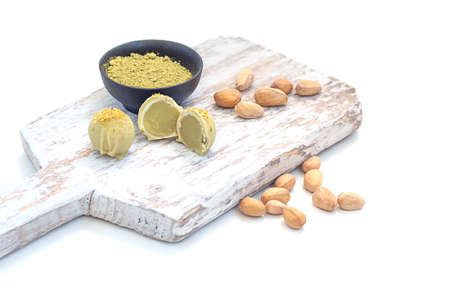 Pistachio matcha white chocolate and candy on a wooden board, on a white background.の写真素材