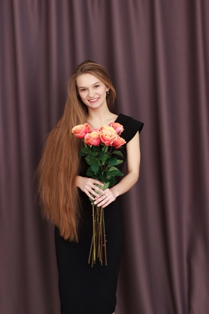 Pretty blonde girl holding a bunch of colouful flowers in her handsの写真素材