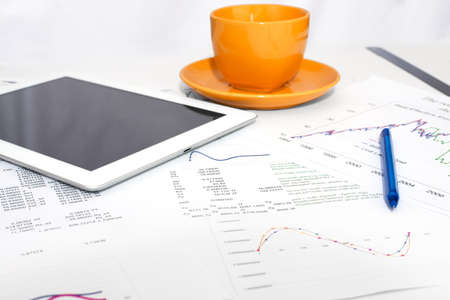 Tablet pc, orange cup and paper with graphs  Business concept