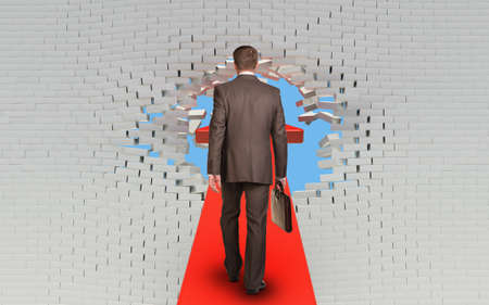 Businessman walking on arrow pierced brick wallの写真素材