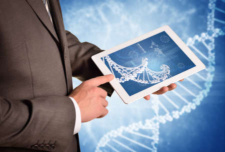 Man hands using tablet pc. Image of DNA helix on tablet screenの写真素材