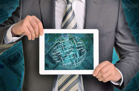 Man hands using tablet pc. Money and sphere of business words on touch screen. Money as backdropの写真素材