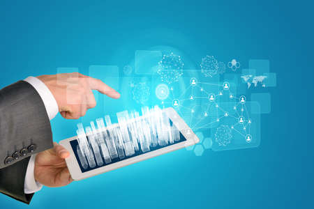Man hands using tablet pc. Wire-frame buildings on touch screen. Virtual elements near computer....