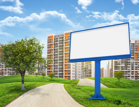 Tall buildings, green hills and road with large billboard against sky with clouds. Architectural conceptの写真素材