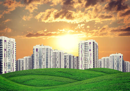 high-rise buildings of same design over green hills with low trees, at sunsetの写真素材