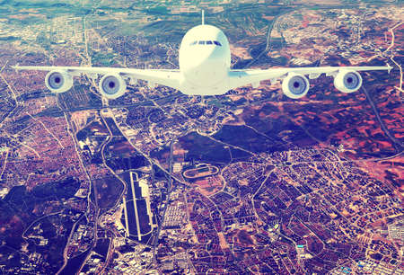 Jet airliner against aerial view of city with suburbs and airport